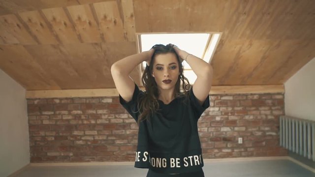 beautiful athletic girl in black dancing vogue or hip hop and jumping. Mid shot