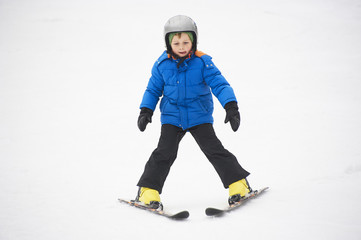 Fototapeta na wymiar Child boy skiing in the mountains on snowy winter day. Kids in winter sport school in resort. Family fun in the snow. Skier learning and exercising on a slope.