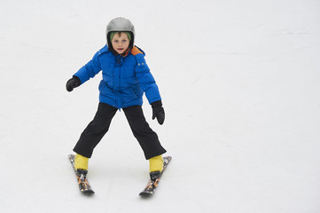 Fototapeta na wymiar Child boy skiing in the mountains on snowy winter day. Kids in winter sport school in resort. Family fun in the snow. Skier learning and exercising on a slope.