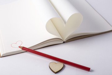 Openning note book white blank page with pen and lovely red ceramic heart shape on white background.