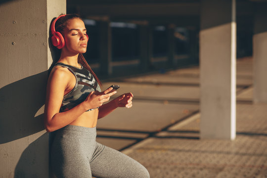 Young woman resting and listen to music after jogging