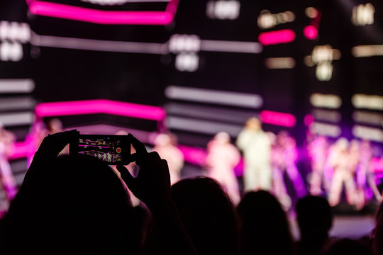 A smartphone held with two hand in order to shoot a footage during a concert.