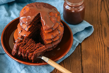 Chocolate pancakes wiyh syrup in a plate on a wooden background. Copy space.