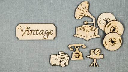 Vintage flat wooden things folded on a grey table. Telephone, phonograph, movie cameras, vinyl records and camera.