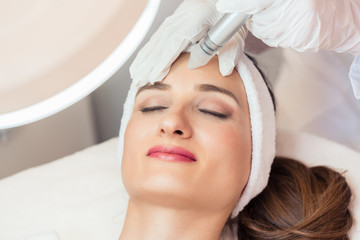 Close-up of the face of a beautiful woman smiling during innovative facial treatment for rejuvenation in a beauty center with modern technology