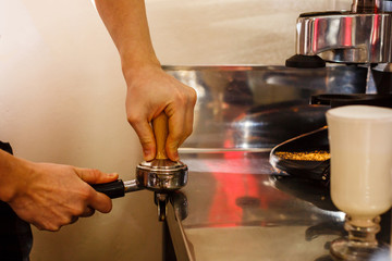 Closeup of male barista hand holding ground coffee for preparing espresso, service and preparation concept.