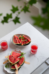 Fresh red smoothie in a glass with sliced pieces of watermelon on table.