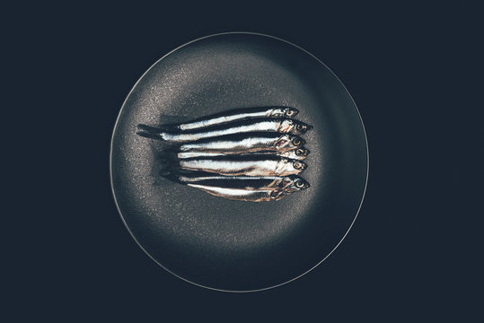 Top view of pile of fish in frying pan isolated on black