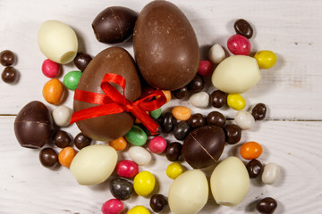 Easter composition with chocolate eggs on white wooden background