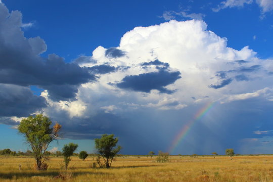 Landscape picture of a rainbow and storm clouds against a blue sky captured during a road trip crossing into Northern Territory, Australia