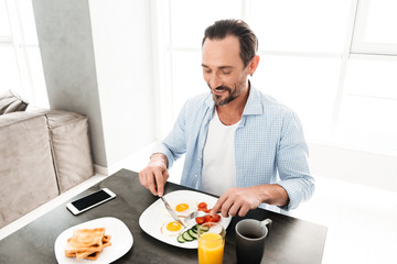 Happy mature man having tasty healthy breakfast