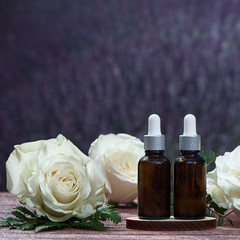 Oil, whey, cream with roses. Organic cosmetics. Roses  and jars on the background of a field of lavender. space for text