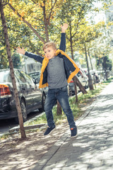 Little boy jumping on the street and catching soap bubbles.
