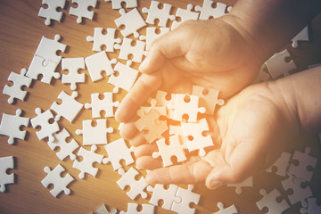 Jigsaw puzzle pieces on palm Pieces of jigsaw puzzle in man hands and one is highlighted,