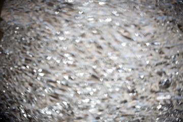 Sparkling spots of figured Bokeh - shining white hearts, water surface is not in focus, background, blue tint
