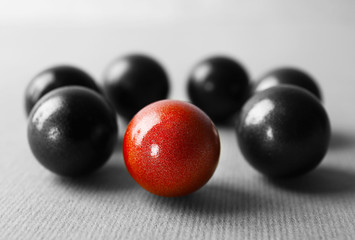 One brown ball among black ones on table. Difference and uniqueness concept