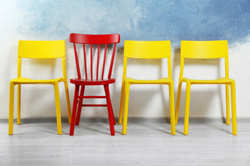One red chair among yellow ones in room. Difference and uniqueness concept