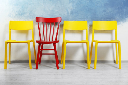 One red chair among yellow ones in room. Difference and uniqueness concept