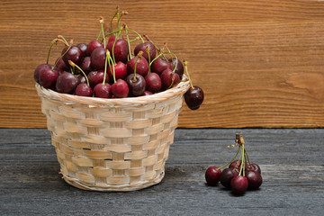 Basket with cherries on a wooden table. Copy space