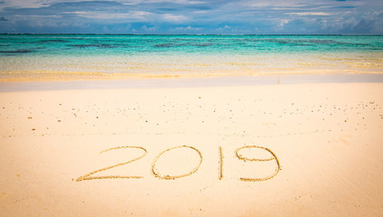 2019 handwritten in sand of tropical beach. New Year's concept.