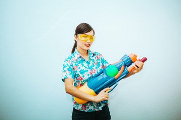 Young beautiful woman holding Songkran thailand festival with gun water colorful on white and blue background.