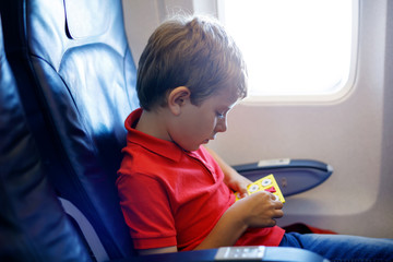 Little kid boy playing tic tac toe game during flight on airplane.