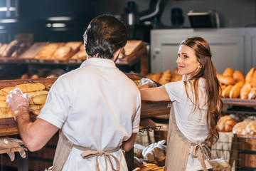 shop assistants arranging loafs of bread in supermarket