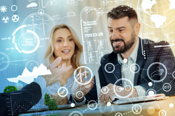 New project. Clever reliable eco engineers sitting at the table and discussing the alternative ways of getting energy while looking at the miniature windmill turbines on the table