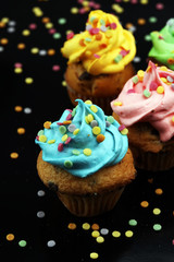 Fototapeta na wymiar Tasty cupcakes on dark background. Birthday cupcake in rainbow colors.