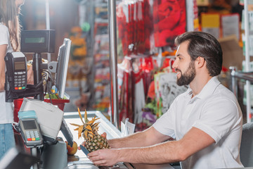 side view of shop assistant at cash point in supermarket