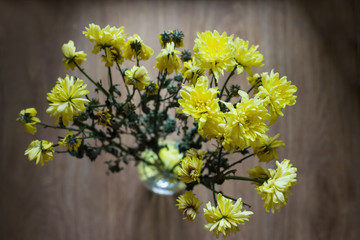Dried and wilted bouquet of yellow chrysanthemums in a glass vase. Conceptual background.