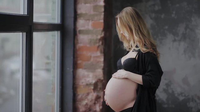 Beautiful young pregnant woman is rubbing her belly.
