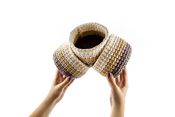 Fototapeta premium Woman's hand is holding a set of colorful crocheted baskets isolated on white background.