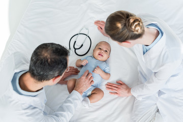 high angle view of pediatricians tickling little baby in bed
