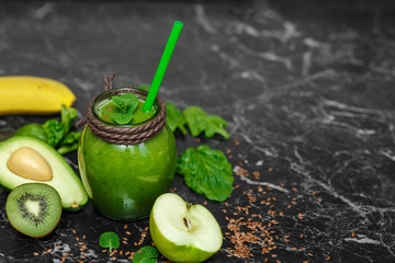 Blended green smoothie with ingredients on table