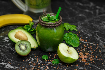 Blended green smoothie with ingredients on table