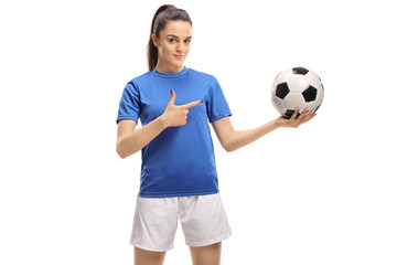 Female soccer player holding a football and pointing