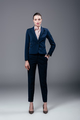 attractive adult businesswoman in stylish suit on grey