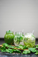Blended green smoothie and infused detox water with cucumber, mint, kiwi spinach and apple for diet healthy eating and weight loss with space for a text. Grey backfround