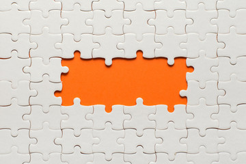 White details of puzzle on orange background and place for inscription