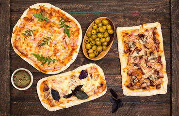 Different kinds of small pizza on rustic wooden background. Various homemade pizza, dinner party at home, top view.