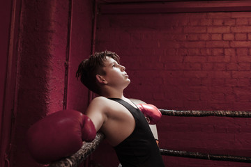 Young boxer taking a break on the ring during training to get his breath back