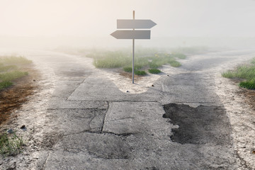 Wegweiser an Weggabelung im Nebel