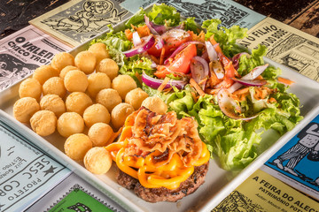 Delicioso hamburguer com cheddar e bacon, acompanhado de batata e salada.