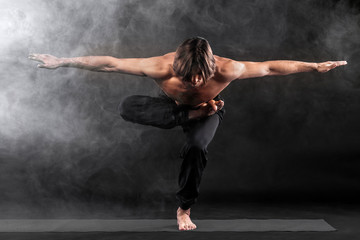 Acroyoga. Young man practicing acro yoga on mat.