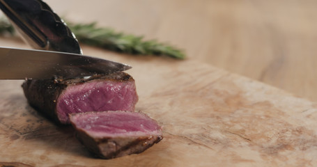 slicing rare fillet mignon steak on wood board
