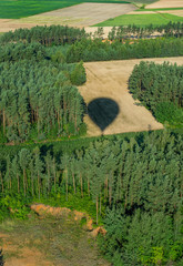 cień balonu turystycznego lecącego nad lasami