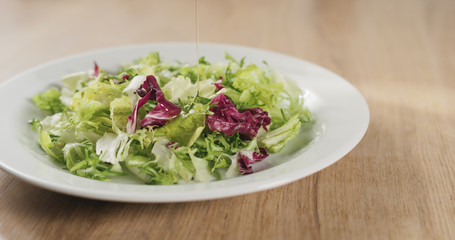 adding olive oil to salad leaves