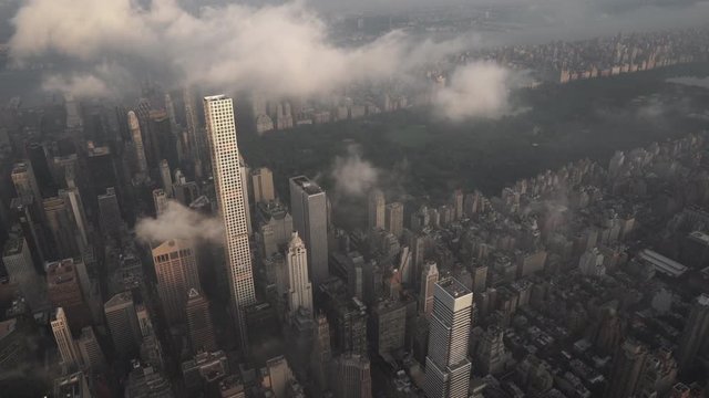 New York City aerial view flying over Midtown Manhattan skyscrapers toward Central Park at sunrise, with fog and low level clouds at sunrise.