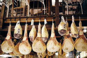 Cured ham hanging from the ceiling of a delicatessen in Bologna  - obrazy, fototapety, plakaty